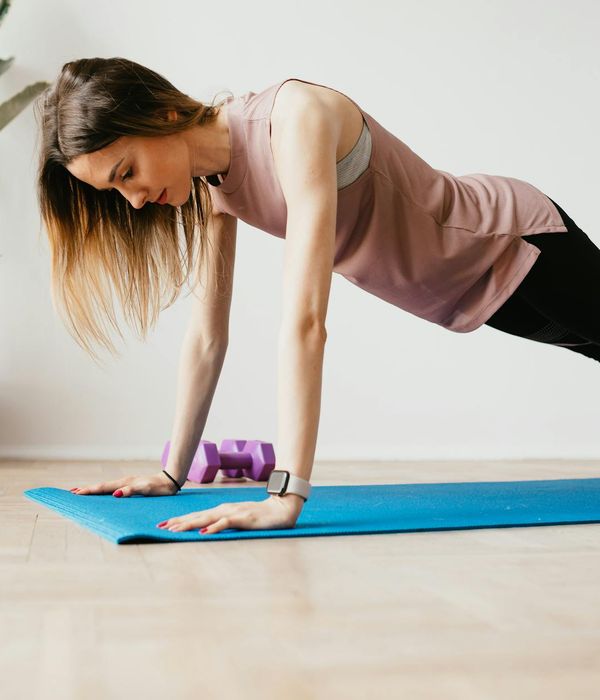 Woman in sportswear feeling vibrant and full of energy in a minimalist room.